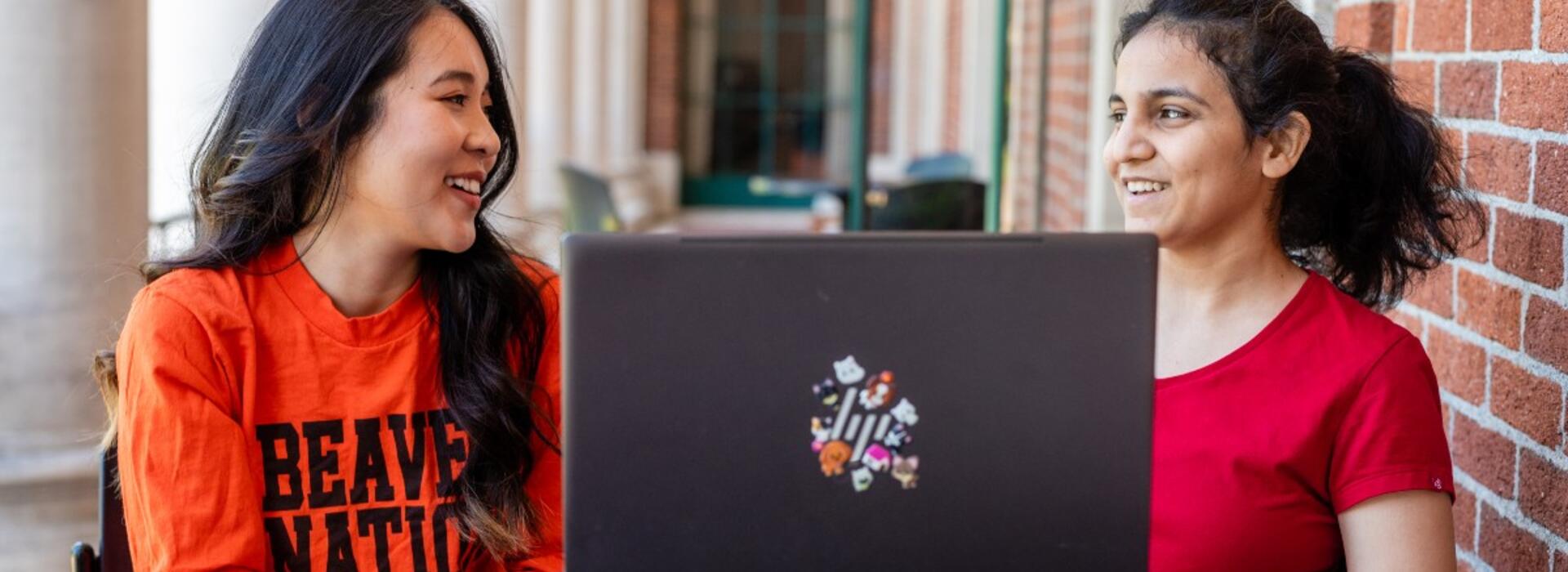 Two international students sitting together with a laptop
